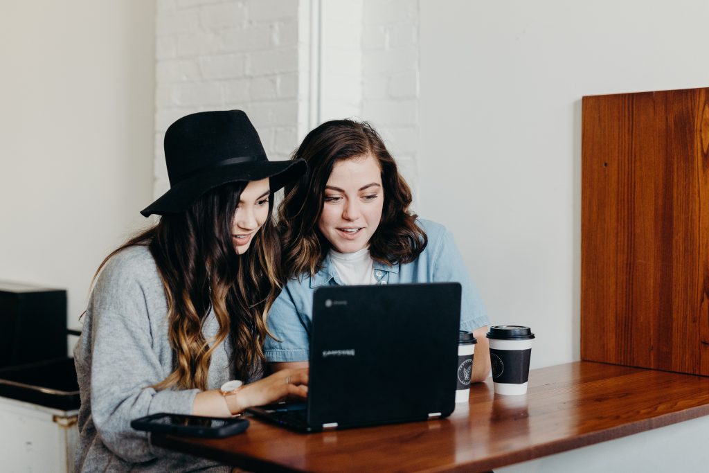 2 girls working on laptop for travel job blogs